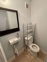 Bathroom entry viewing left side of bathroom with Toilet, Sink, Mirror, and extra Storage