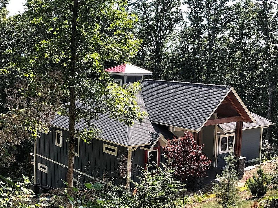 OUR CONTEMPORARY TREE HOUSE IS A 2 STORY HOME, BUILT ON A SLOPE WITH A WALKOUT BASEMENT AND 2 CAR GARAGE BELOW AND A CUPOLA WITH A LITTLE RED MEDAL ROOF ABOVE. THERE ARE 2 DRIVEWAYS: ONE IN FRONT FOR VISITORS AND ONE BELOW THAT LEADS TO THE GARAGE