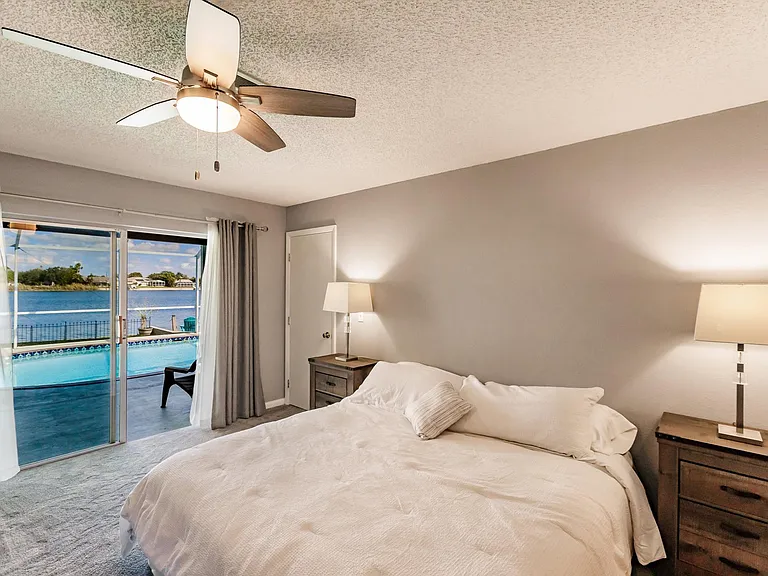 Master bedroom to huge sliding doors opening to covered patio and pool over looking lake.