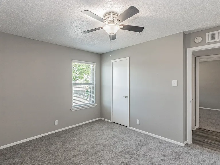 Comfortable bedroom with ceiling fan and soft carpeting