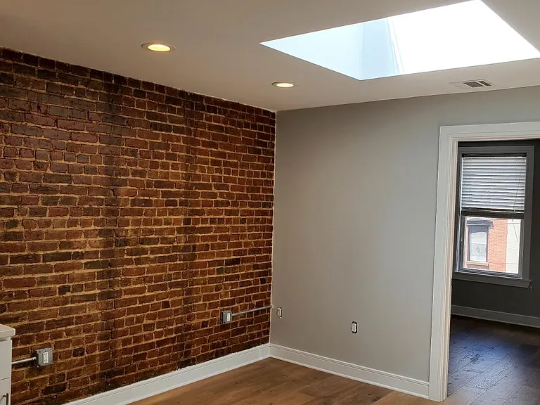 Living room with exposed brick and skylight