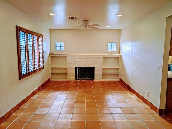 Living room with ceiling fan, built-in shelves, plantation shutters