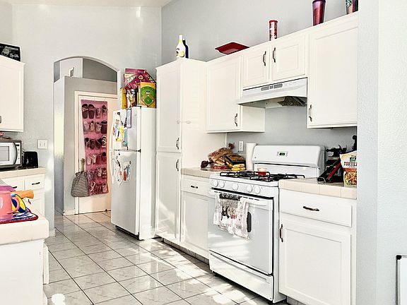 Kitchen with Tiles and lots of windows. Dishwasher, Two Fridges (one in garage) stove.
