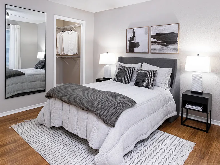 Unwind in a cozy bedroom featuring wood-style flooring, soft lighting, and a spacious walk-in closet.