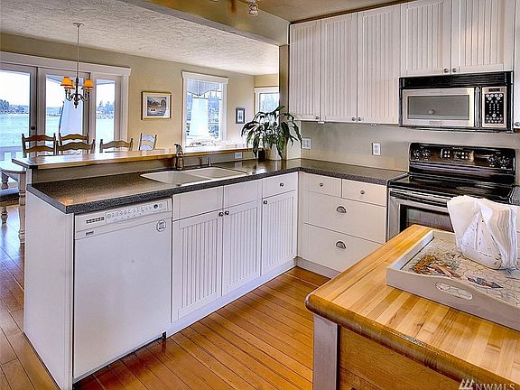 Kitchen features bay views, butcher block bar top, wainscotting with chair rail, fir floors and access to the lower level.