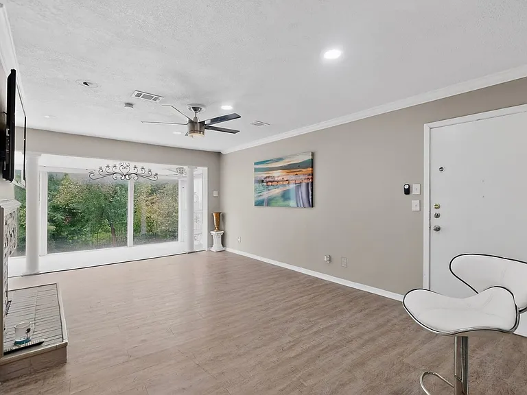 Bright living room with a ceiling fan, situated beside the sun room; perfect for relaxation and comfort.
