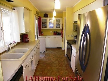 Kitchen with pendant lighting, stainless steel appliances, glass backsplash, built in china cupboard and laundry chute to the laundry room.
