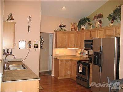 The kitchen has stainless appliances, hardwood floors, under-the-cabinet lighting and vaulted ceilin