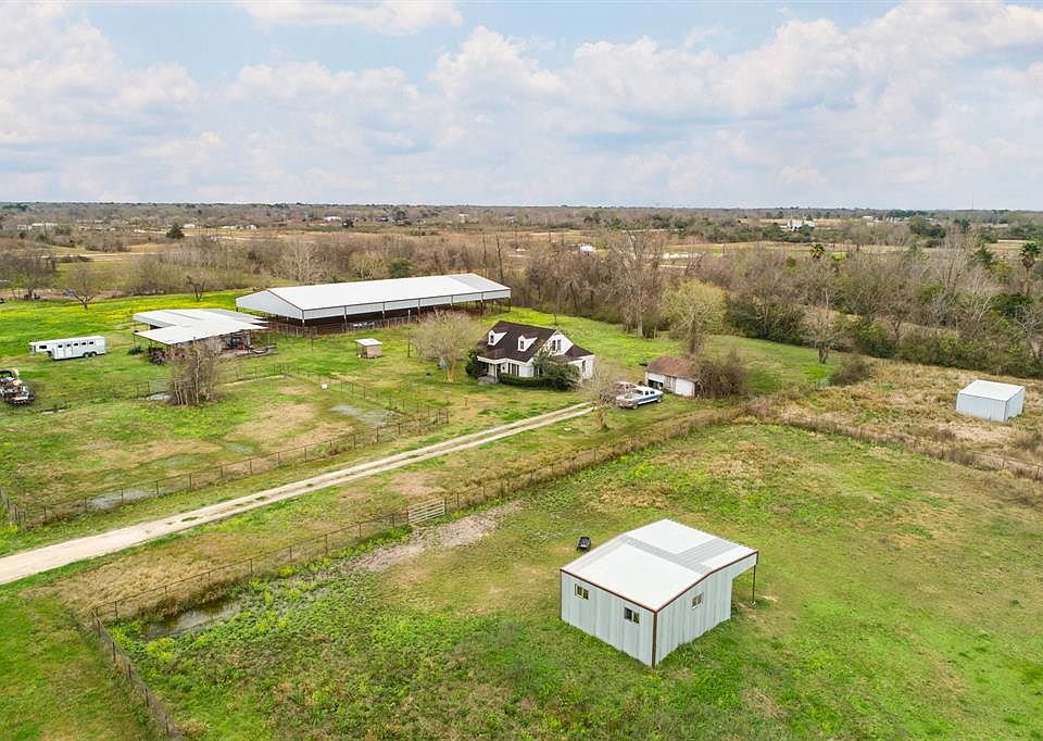 Aerial view of 304 Hawkins showing three horse traps/paddocks, two shed barns, farm house, 6-stall horse barn and covered, lighted riding arena. Photo does not show the entire property!