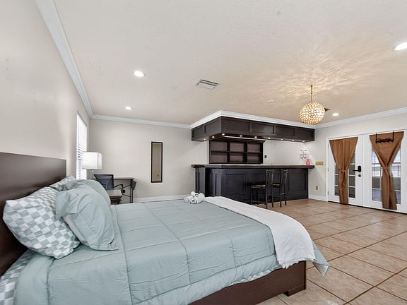 Spacious bedroom suite with a dedicated desk area, built-in bar with seating, and French doors for added access and light.