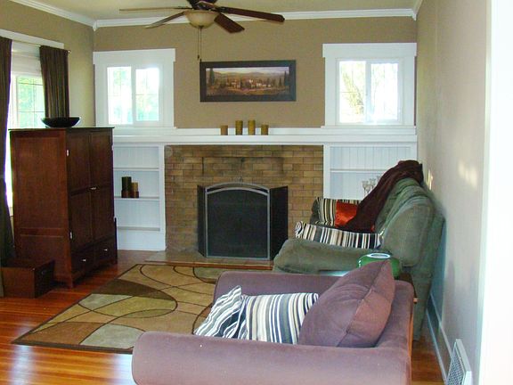 living room with wood burning insert, built-ins, vinyl windows