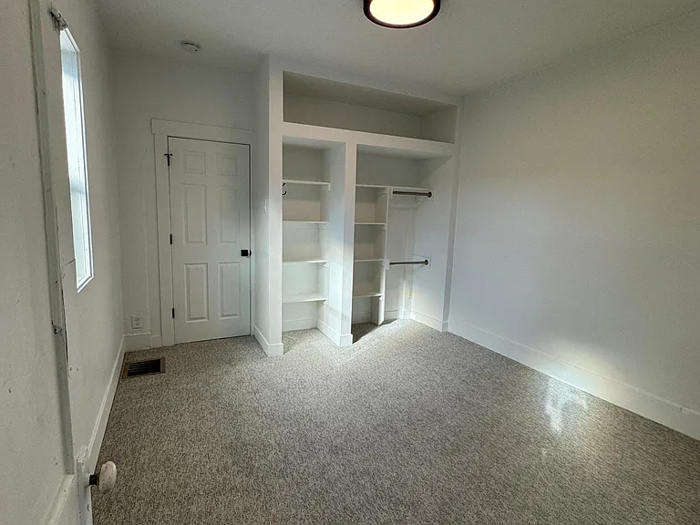 Spacious second bedroom featuring plush carpet and convenient built-in shelving/storage.