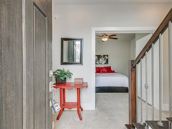 Welcome in. This entry with terazzo flooring greets you with a wonderfully bright space opening up to a handsome staircase with hardwood risers and a decorative metal and wood banister. In this photo a door to the right of the staircase opens to the 