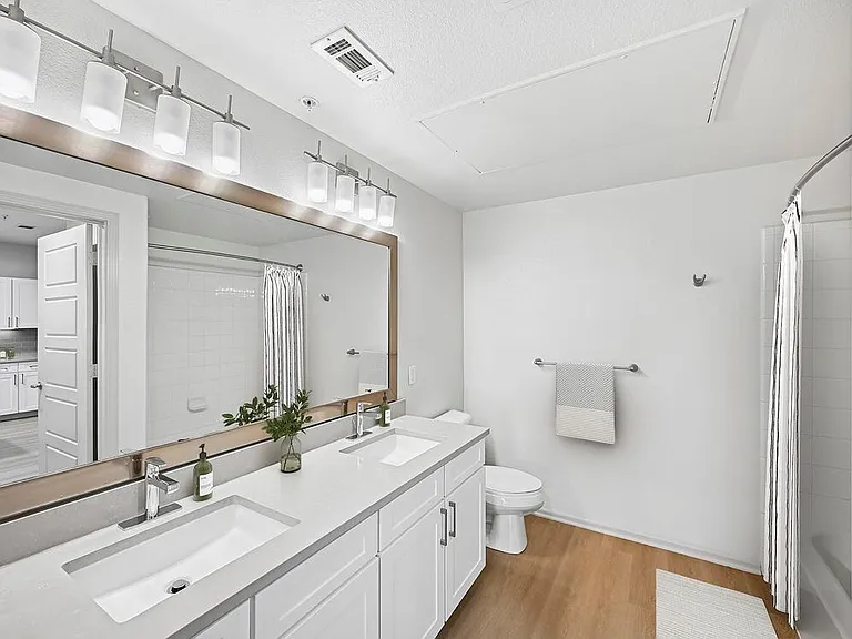 Renovated Package I bath with white cabinetry, grey quartz countertops, and hard surface flooring