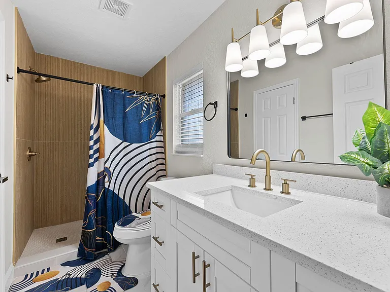 Updated bathroom with a wide vanity, quartz-style countertop, and walk-in shower, plus a window for ventilation.