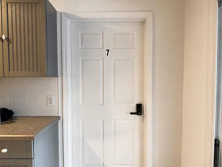 Interior hallway/entry area with a numbered door and keyless entry, adjacent to a built-in cabinet and counter workspace.