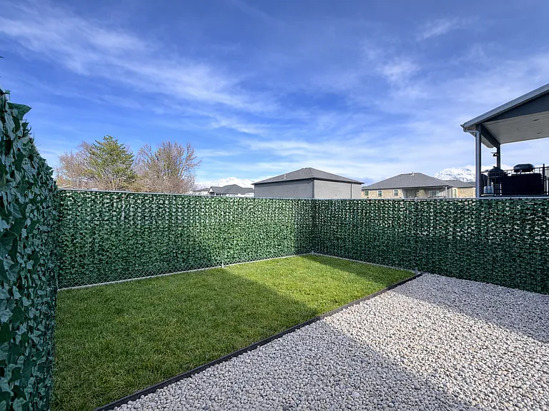 Fully fenced Spacious private backyard with fresh grass, clean gravel area, and full privacy fencing.