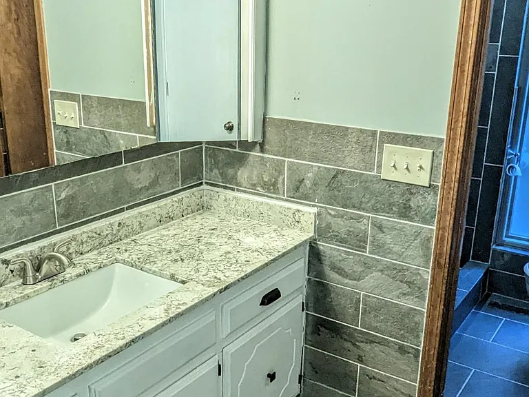 Remodeled guest bathroom with granite countertops and modern cabinet hardware. Well-lit, automatic lighting.