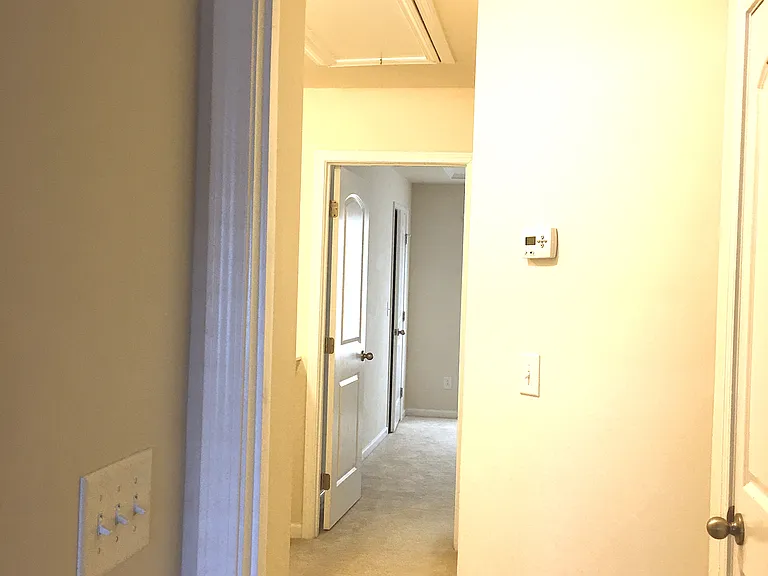 Hallway with Bedroom suits on opposite ends. House features split air-conditioner for each floor with its own thermostat regulation. Wall features thermostat #2