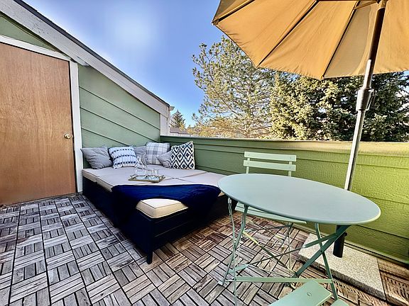 Balcony with double recliner, bistro table, chairs, and umbrella