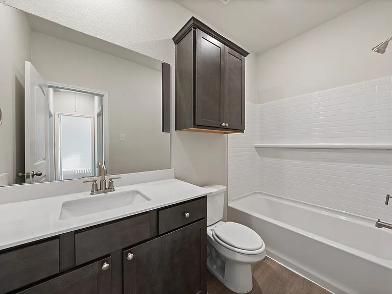 The secondary bathroom has a large vanity space and shower-tub combo.