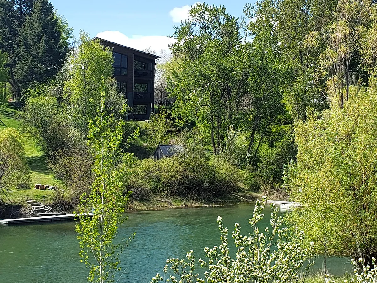 View of condo building from across the trail on the Whitefish River. The subject unit is ground floor with walkout patio - 2nd St W