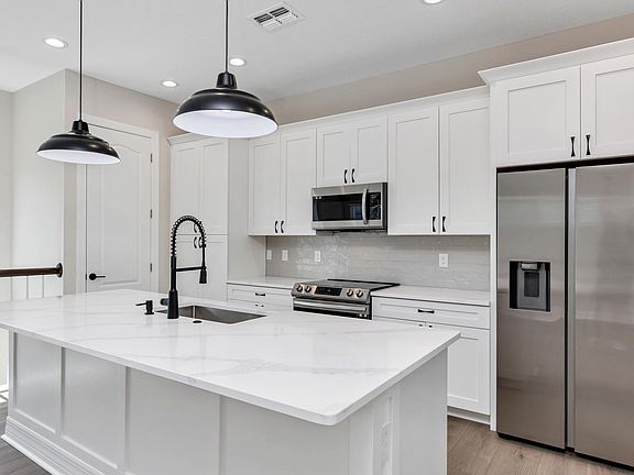 View of most of the kitchen that includes the island, cabinets, and appliances. Facing north west.