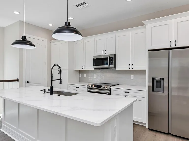 View of most of the kitchen that includes the island, cabinets, and appliances. Facing north west.