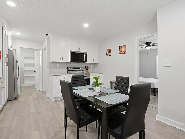 Eat-in kitchen with ample white cabinetry, pantry storage, and stainless appliances, plus a dining set for four.