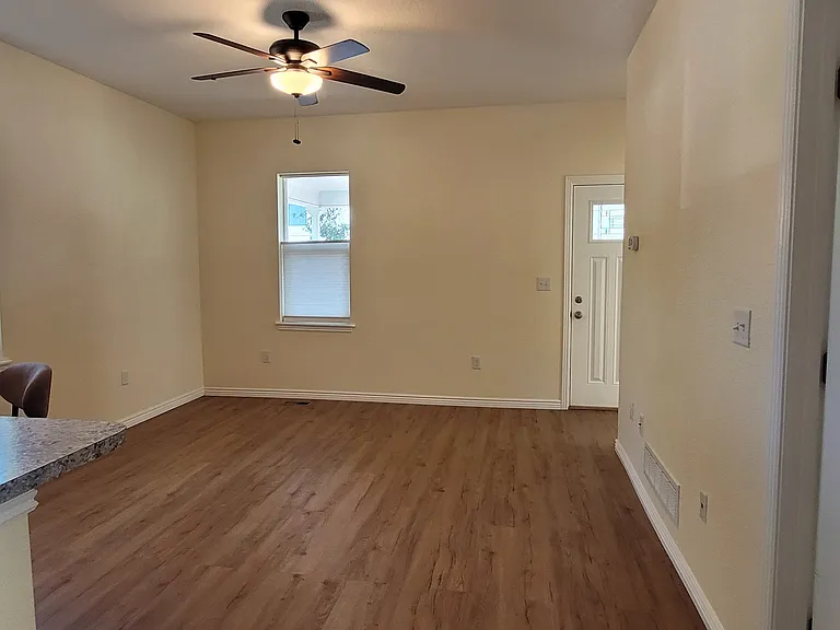 Living room with front door and window to the North, and side window to the West, ceiling fan