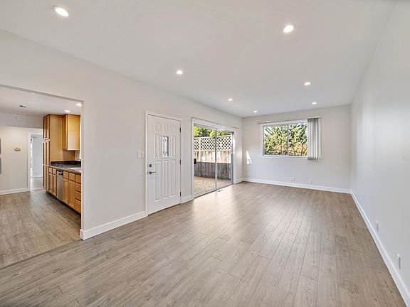 View from dining room area showing kitchen entrance, front door and sliding glass to deck