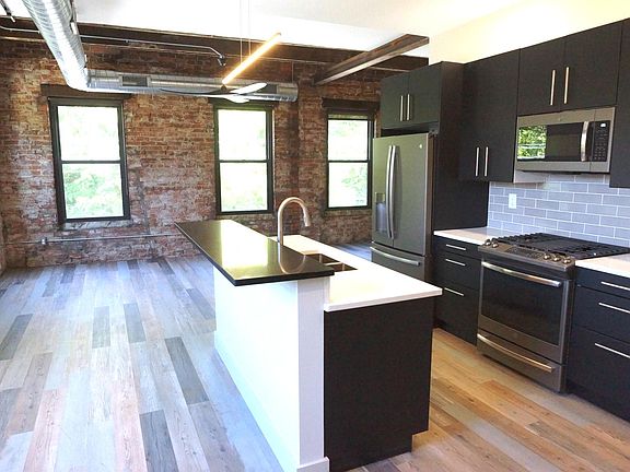Contemporary kitchen and living area with ceiling fan.