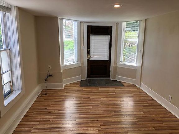 Living room with bay windows, hardwood floors, slate entry with antique wood door.