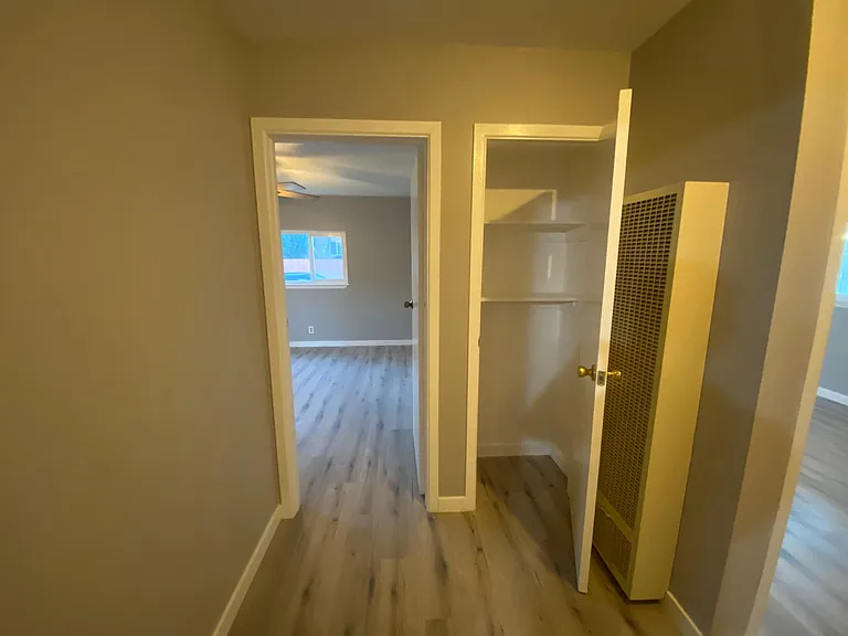 Hallway to bedrooms, with storage closet and wall heater.