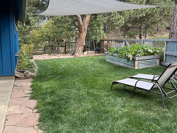 Fenced in front yard with raised garden bed, stone patio, and view of Porphyry mountain.