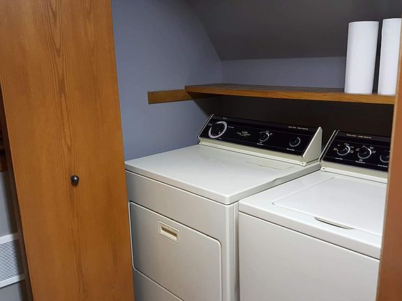 Washer and dryer laundry center closet . Nice shelving for storage and a rod inside this closet to hang clothes .