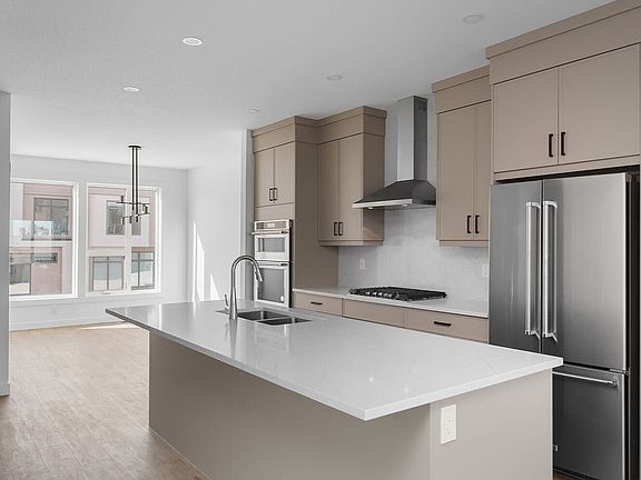 Modern kitchen featuring warm-toned cabinetry, a spacious quartz island, and high-end stainless stee