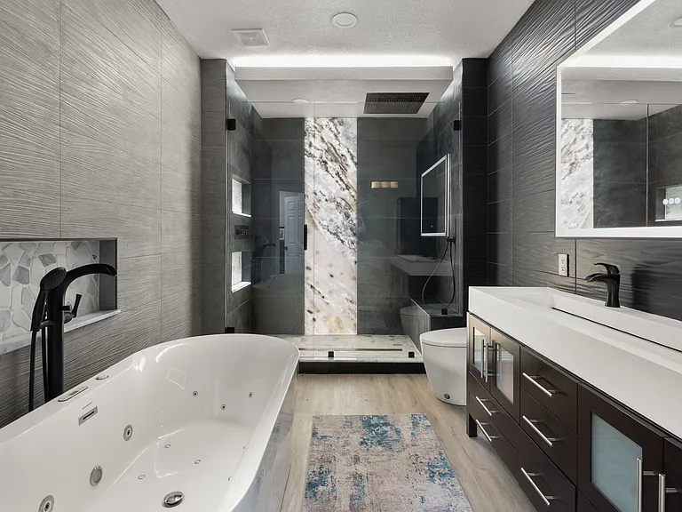 Spa-style bathroom with a freestanding soaking tub, dual-sink vanity, and a glass walk-in shower with built-in niches.