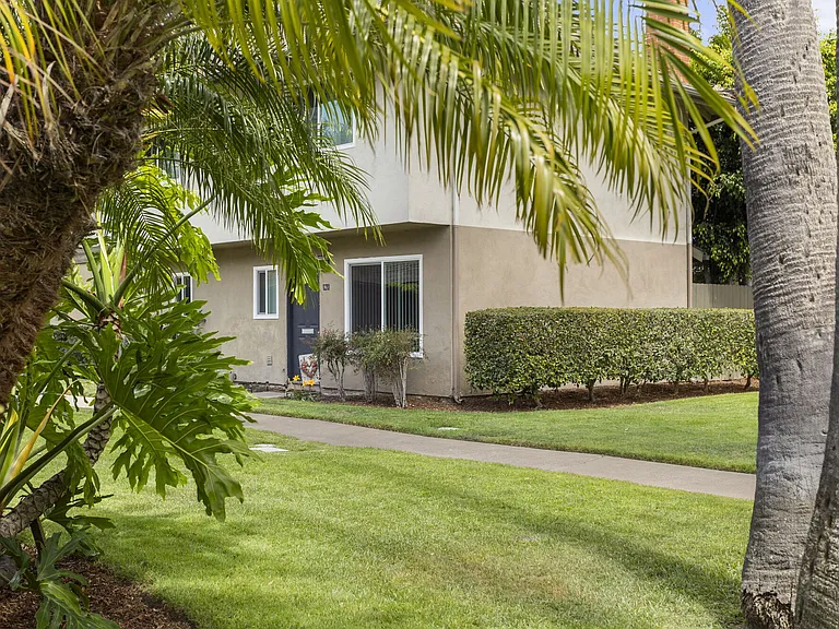 Walking paths through tropical landscaping at Mango Tree Apartments in Santa Ana, CA