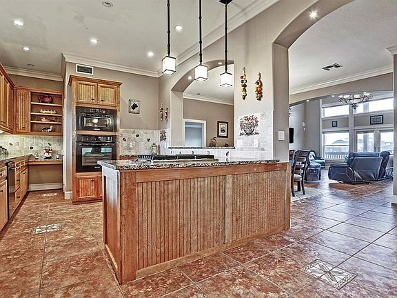 An inviting entryway leads to an open living/kitchen/dining concept featuring tile floors with custom inlays, fireplace, gorgeous chandelier, soaring ceilings & skylights allowing rays of sunlight.