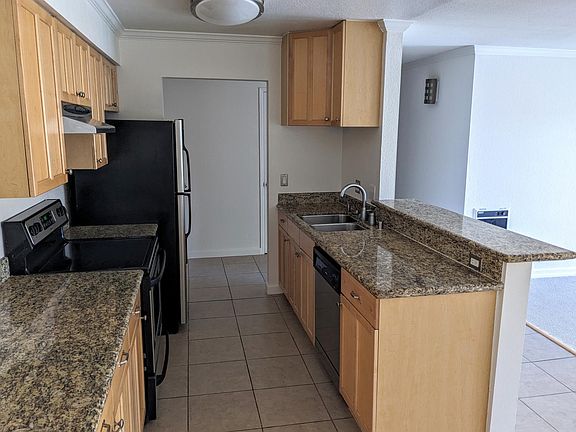 Kitchen equipped with dishwasher, double stainless steel sink, garbage disposal, electric range and hood.
