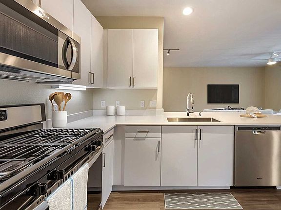 Renovated Package I kitchens with light grey quartz countertops, new white cabinetry, stainless steel appliances, upgraded fixtures, and hard surface flooring throughout