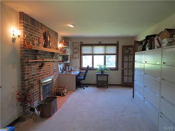 living room with brick fireplace used as an office with French doors to front entry