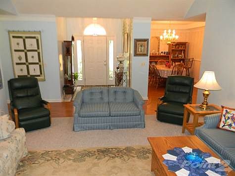 A spacious living room with cathedral ceiling and ceiling fan.