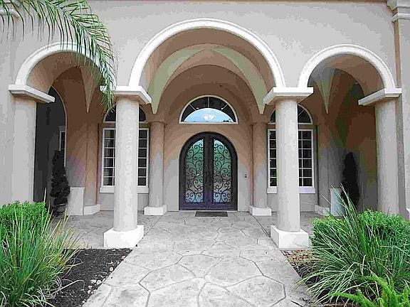 Welcoming entrance with oversized covered entry and custom double wrought iron doors.
