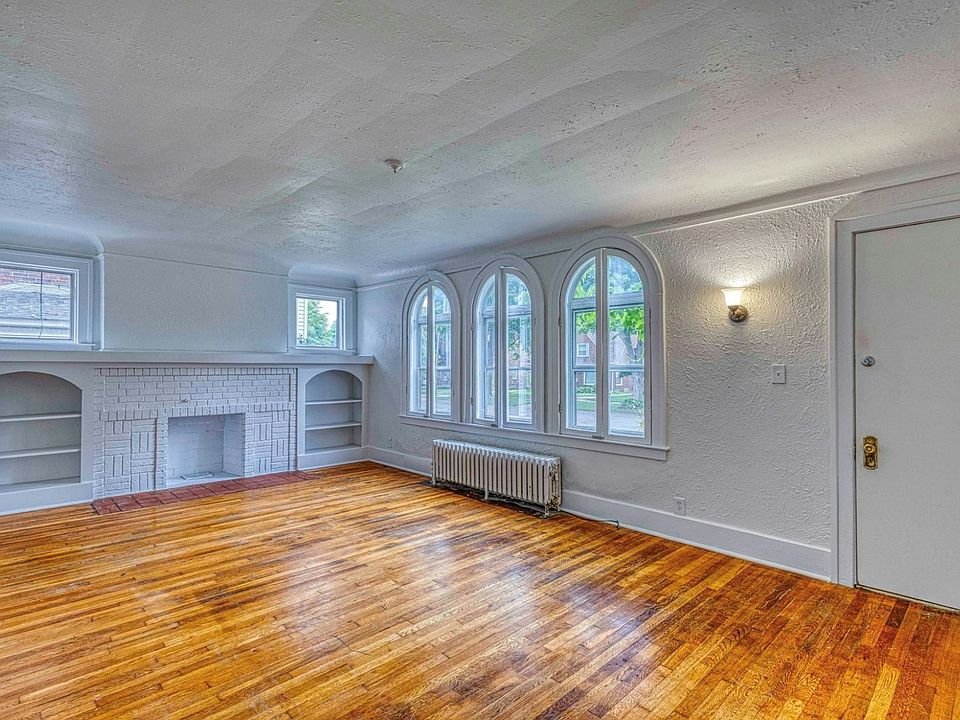 3 large beautiful ornate windows allow ample natural light to welcome you into the freshly repainted room with original hardwood flooring, decorative fireplace and built-in surrounding shelving