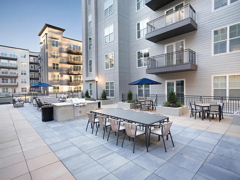 An open-air courtyard at Modera Liberty Row features outdoor dining, grilling stations, and lounge seating designed for everyday gatherings in the heart of Charlotte.