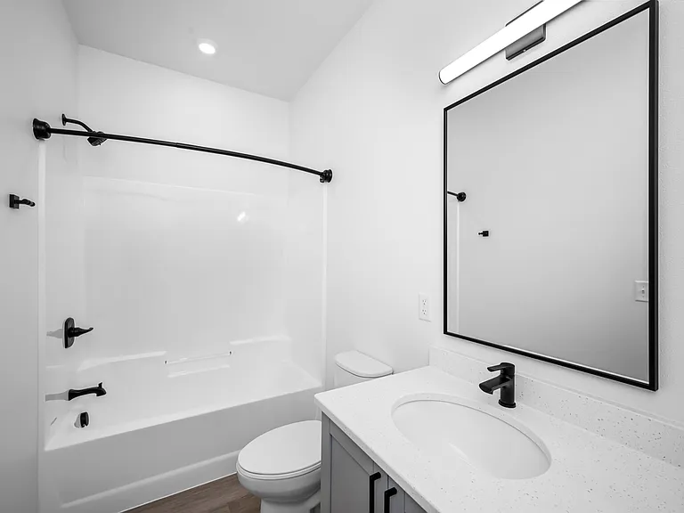 Modern bathroom showcasing sleek fixtures, a spacious bathtub with elegant black hardware, and a chic vanity with illuminated mirror. Modern bathroom showcasing sleek fixtures, a spacious bathtub with elegant black hardware, and a chic vanity with illumin