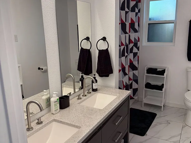 Shared bathroom has double sinks and a tub with shower