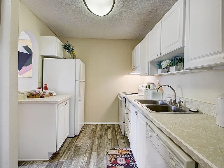 Charming kitchen with white cabinetry, modern appliances, and stylish wooden flooring, perfect for culinary enthusiasts.